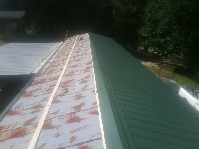 Old rusted panels beside newly installed green metal roofing — Wind Damage Roof Repair by Roofing Brothers in South Pittsburg