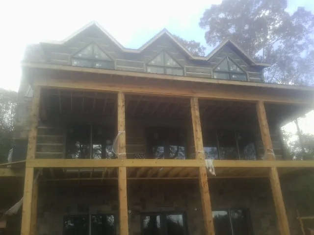 Dormers and porch framing on a large log home under construction — Roof Coating work by our crew in South Pittsburg