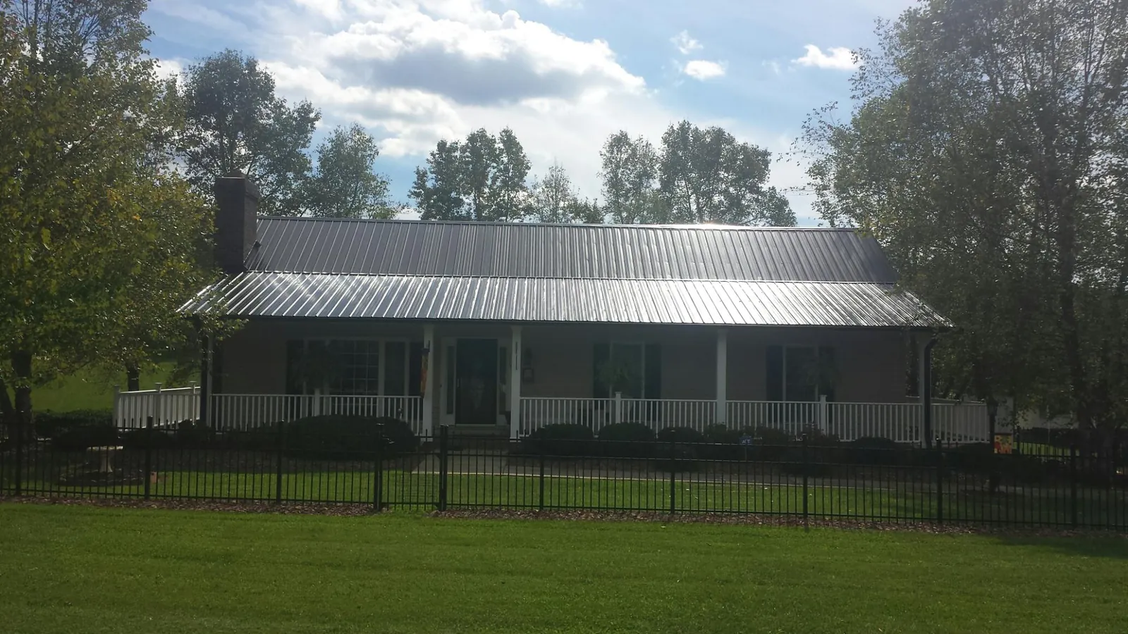 Gray metal roof on a brick ranch with a full width front porch — Gutter Guard Installation work by our crew in South Pittsburg
