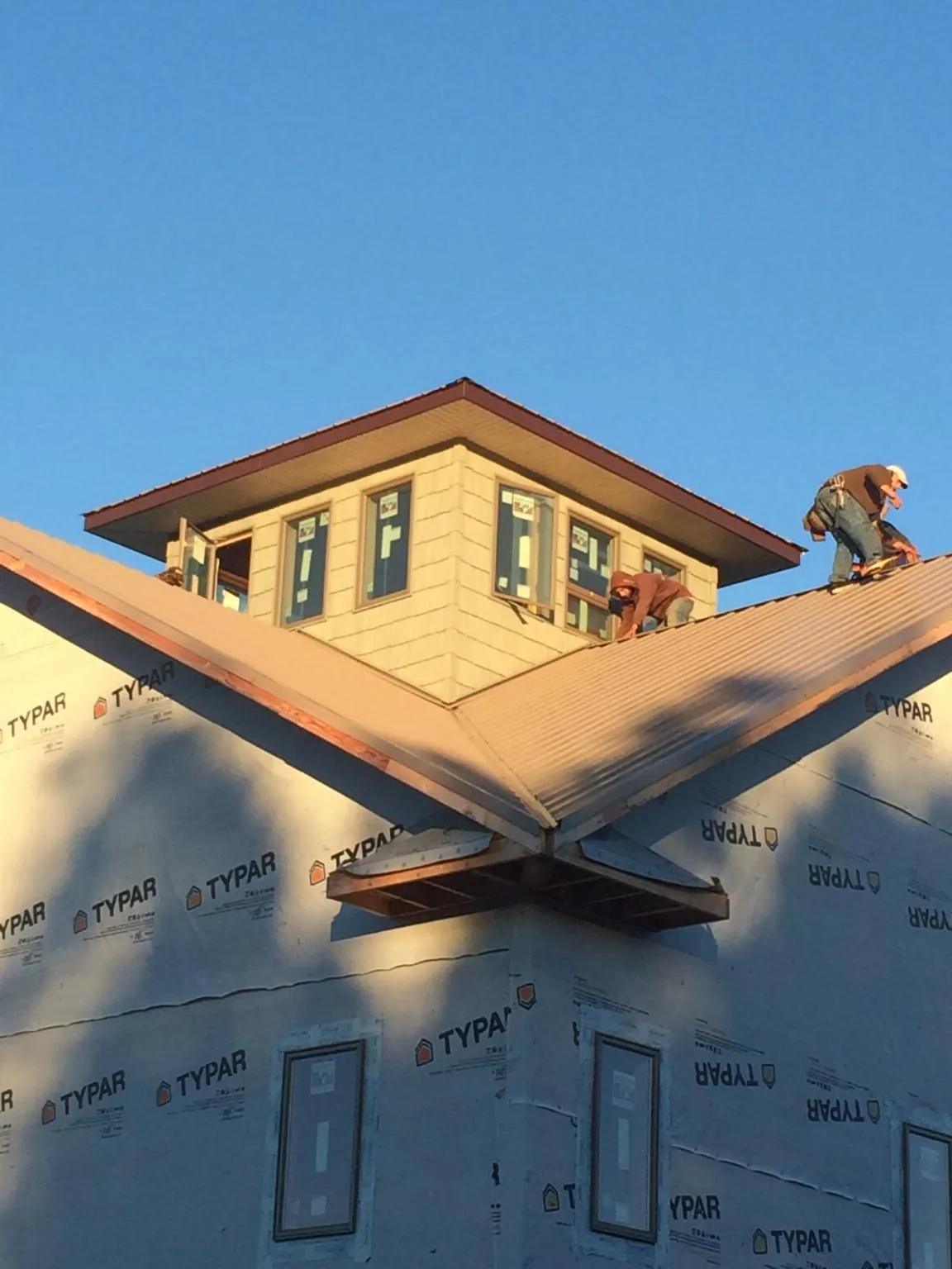 Roofers working around a rooftop cupola on a new metal roof at sunset — Roof Waterproofing in South Pittsburg by Roofing Brothers